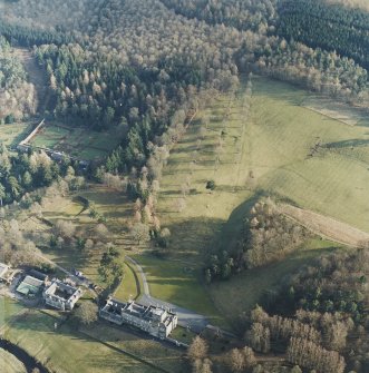 Oblique aerial view centred on the country house with stables and greenhouse adjacent, taken from the NNW.