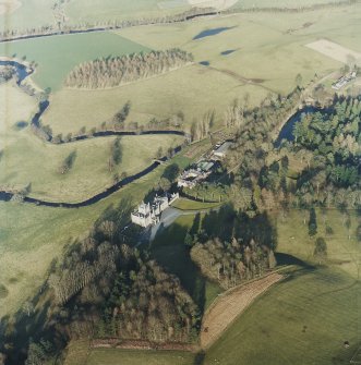 Oblique aerial view centred on the country house with stables and bridge adjacent, taken from the SW.