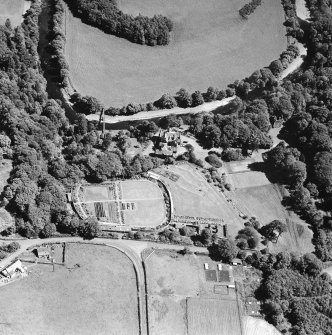 Oblique aerial photograph of Knockdolian Castle taken from the NW, centred on the country house and policies with the tower house in the trees.