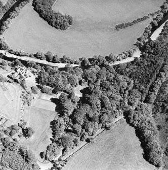 Oblique aerial photograph of Knockdolian Castle taken from the W, centred on the country house and policies with the tower house in the trees.