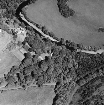 Oblique aerial photograph of Knockdolian Castle taken from the SSW, centred on the country house and policies with the tower house in the trees.
