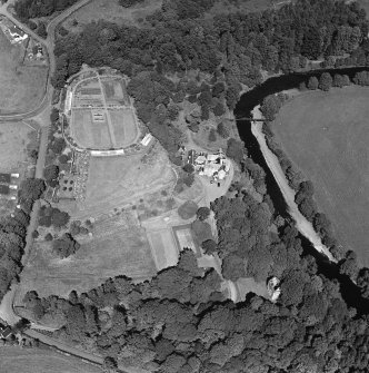 Oblique aerial photograph of Knockdolian Castle taken from the S, centred on the country house and policies with the tower house in the trees.