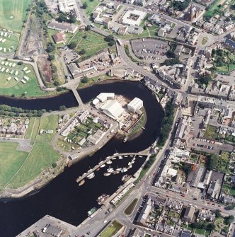 Oblique aerial view centred on the boatbuilding yard and harbour, with the church and burial-ground adjacent, taken from the WSW.