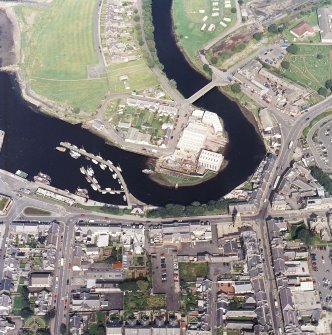 Oblique aerial view centred on the boatbuilding yard and harbour, with the church and burial-ground adjacent, taken from the S.