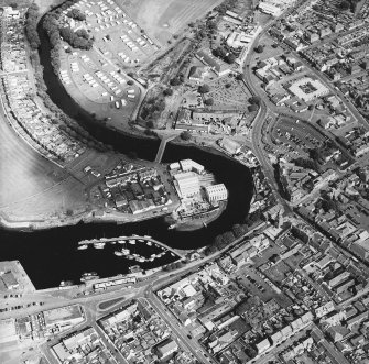 Oblique aerial view centred on the boatbuilding yard and harbour, with the church and burial-ground adjacent, taken from the SW.