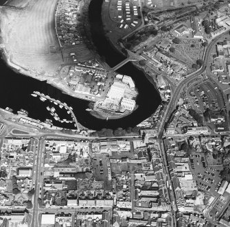 Oblique aerial view centred on the boatbuilding yard and harbour, with the church and burial-ground adjacent, taken from the SSW.