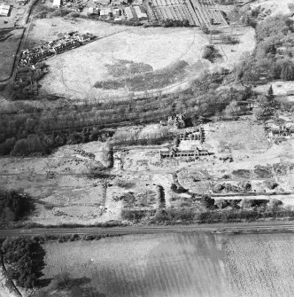 Oblique aerial view centred on the remains of the former hospital, the west wing and west corridor of the hospital, and church, taken from the SE.