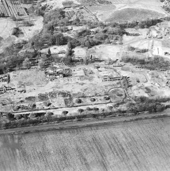 Oblique aerial view centred on the remains of the former hospital, the east and west corridor links of the hospital, the east wing, and church, taken from the SSE.