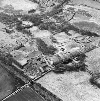 Oblique aerial view centred on the remains of the former hospital, the east wing and east corridor of the hospital, and church, taken from the E.