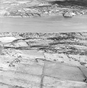 General oblique aerial view looking across the remains of an anti-aircraft battery towards Dumbarton Rock, taken from the SSW.