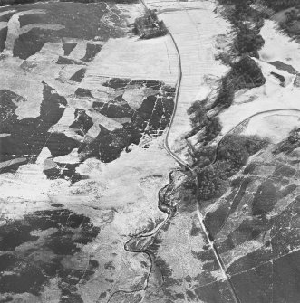 Oblique aerial view centred on the remains of rig with buildings, enclosures, road bridge and farmsteading adjacent, taken from the NW.