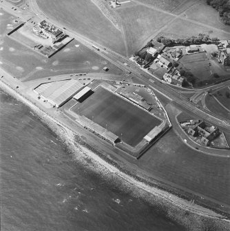 Oblique aerial view centred on the football ground with school adjacent, taken from the SE.
