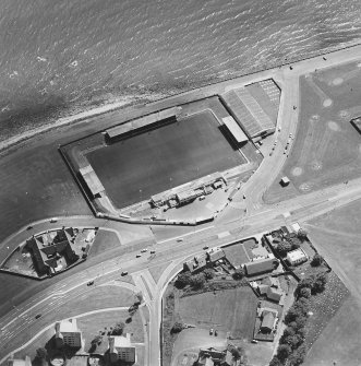Oblique aerial view centred on the football ground with school adajacent, taken from the N.