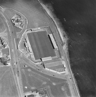 Oblique aerial view centred on the football ground with the school adjacent, taken from the W.