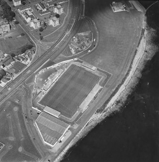Oblique aerial view centred on the football ground with the school adjacent, taken from the SW.