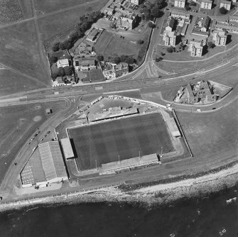 Oblique aerial view centred ont he football ground with the school adjacent, taken from the S.