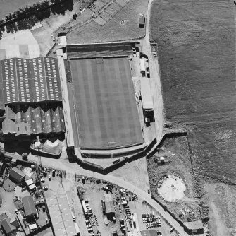 Oblique aerial view centred on the football ground with market adjacent, taken from the E.