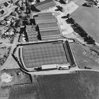 Oblique aerial view centred on the football ground with market adjacent, taken from the NNE.