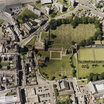 Oblique aerial view centred on the remains of the abbey and churchyard, taken from the SSE.
