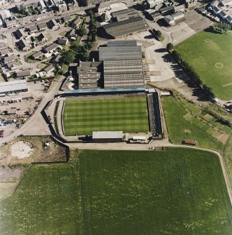 Oblique aerial view centred on the football ground with market adjacent, taken from the N.