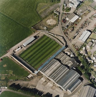 Oblique aerial view centred on the football ground with market adjacent, taken from the SW.