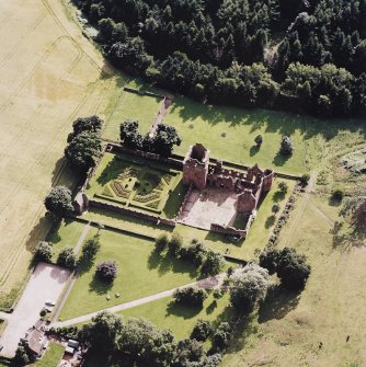 Oblique aerial view centred on the remains of the castle, and the walled garden and custodian¿s house, taken from the NE.