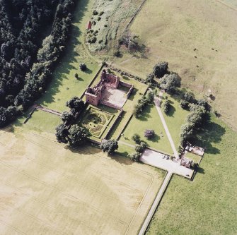 Oblique aerial view centred on the remains of the castle, and the walled garden and custodian¿s house, taken from the SE.