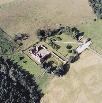 Oblique aerial view centred on the remains of the castle, and the walled garden and custodian¿s house, taken from the SSW.