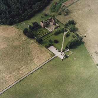 Oblique aerial view centred on the remains of the castle and gardens with custodians house adjacent, taken from the E.