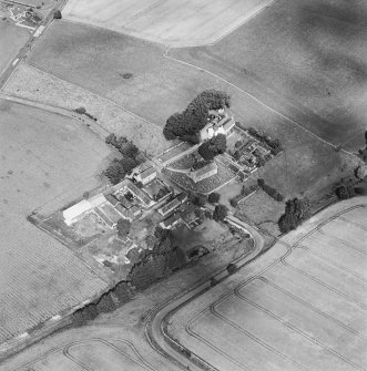 Oblique aerial view centred on the church and burial ground with manse, schoolhouse, farmsteading and road bridge adjacent, taken from the S.