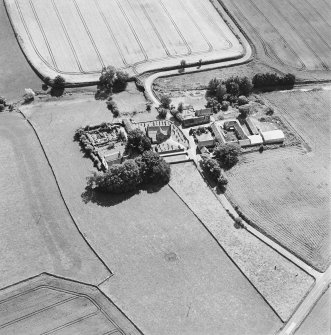 Oblique aerial view centred on the church and burial ground with manse, schoolhouse, farmsteading and road bridge adjacent, taken from the N.