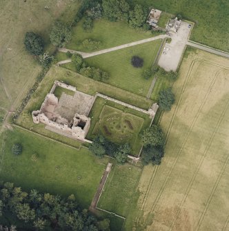Oblique aerial view centred on the remains of the castle, and the walled garden and custodian¿s house, taken from the SW.