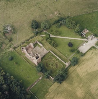 Oblique aerial view centred on the remains of the castle, and the walled garden and custodian¿s house, taken from the SSW.