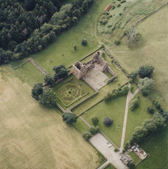 Oblique aerial view centred on the remains of the castle, and the walled garden and custodian¿s house, taken from the E.
