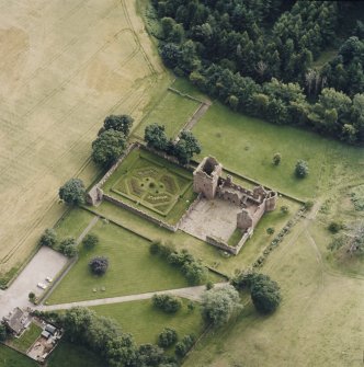 Oblique aerial view centred on the remains of the castle, and the walled garden and custodian¿s house, taken from the NE.