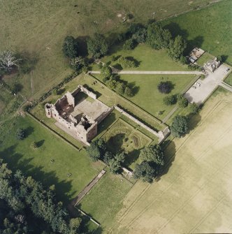 Oblique aerial view centred on the remains of the castle, and the walled garden and custodian¿s house, taken from the SW.