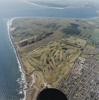 Oblique aerial view of Carnoustie golf course with the ranges and training area in the background, taken from the NE.