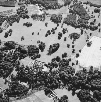 Oblique aerial view centred on the cropmarks of avenues leading to the country house, taken from the NE.