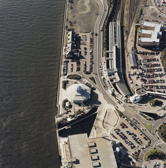 Oblique aerial view centred on the harbour and the Discovery visitor centre, with the leisure centre and railway station adjacent, taken from the NE.