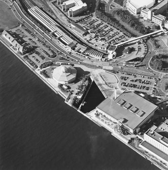 Oblique aerial view centred on the harbour and the Discovery visitor centre, with the leisure centre and railway station adjacent, taken from the E.