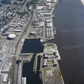 Oblique aerial view centred on the dock and oil refinery with the dock, wharf and gasworks adjacent, taken from the SW.