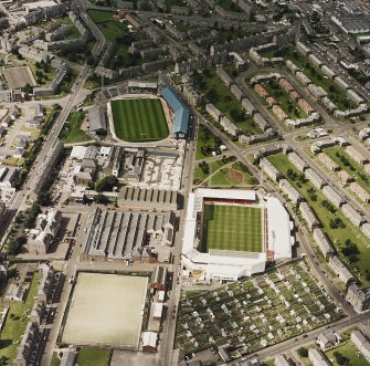 Oblique aerial view of Dundee centred on the stadium with stadium and jute works adjacent, taken from the SE.