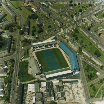 Oblique aerial view centred on the football stadium with jute works adjacent, taken from the SE.