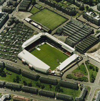 Oblique aerial view centred on the football stadium with jute works adjacent, taken from the N.