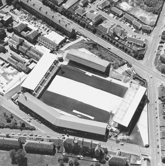Oblique aerial view centred on the football stadium with jute works adjacent, taken from the N.