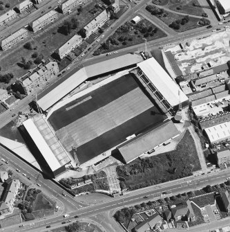 Oblique aerial view centred on the football stadium with jute works adjacent, taken from the SW.