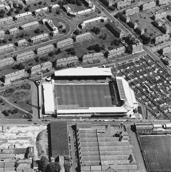 Oblique aerial view centred on the football stadium with jute works adjacent, taken from the SW.