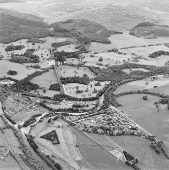 Oblique aerial view of Blair Castle centred on the country house, with Blair Atholl village and a road bridge adjacent, taken from the SE.