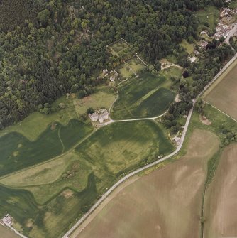 Oblique aerial view of Castle Menzies centred on a tower house, well, walled garden and military road, and the crop marks of pits, a garden and linear cropmarks, taken from the SSW.