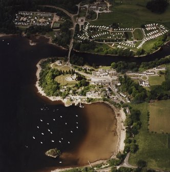 Oblique aerial view of Kenmore centred on the road bridge, church and hotel, and the remains of a crannog with Kenmore Village adjacent, taken from the SW.